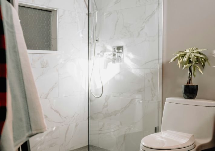 Professional deep cleaning services for a modern bathroom with a glass shower and marble tile.