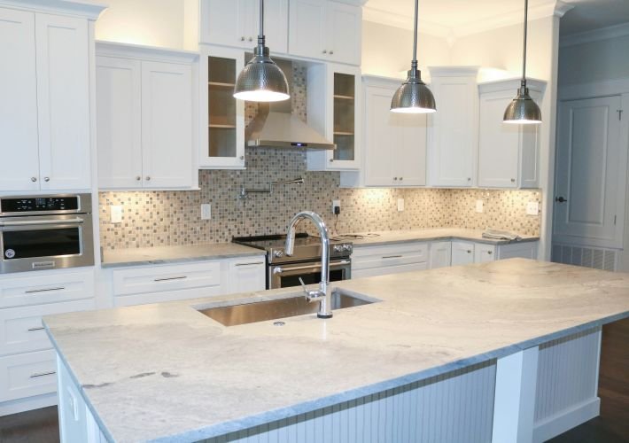 A professional move-in cleaning of a modern kitchen with white cabinets and a clean marble countertop.