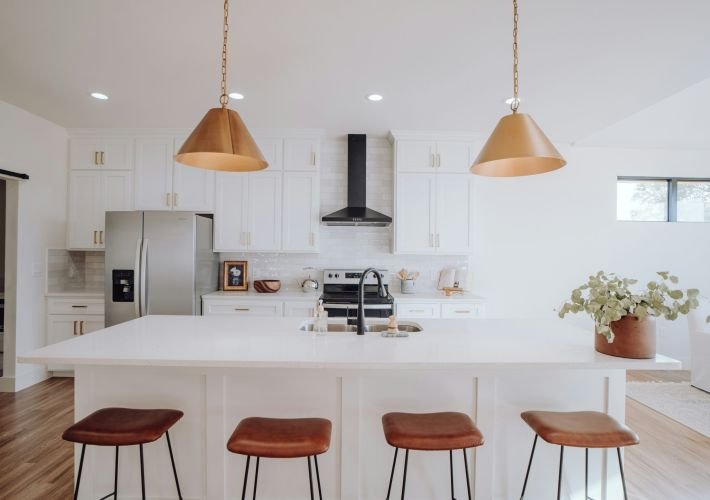 An immaculate, professionally cleaned white kitchen with a large island and stainless steel appliances.